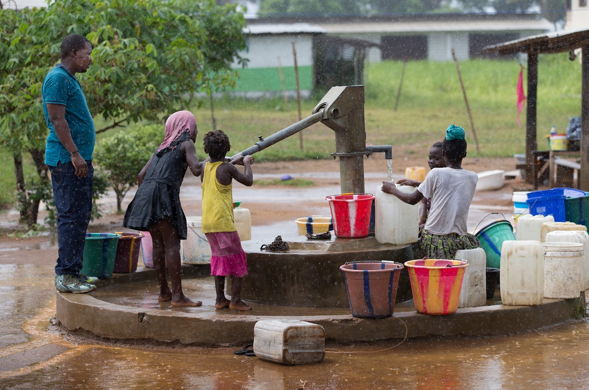 Jefferson B. Knight (left) checks on the output of a water well during the rainy season in Robert's Town Village near Marshall City, Liberia. Knight is director of the Peace With Justice Program for the United Methodist Liberia Conference. Photo by Mike DuBose, UMNS.