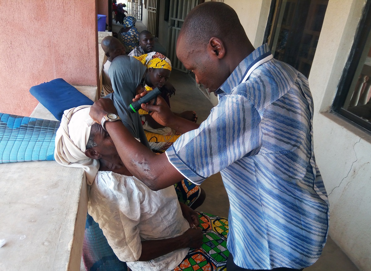 A woman has her eyes examined by a medical attendant while other patients sit waiting in line at Gwandum Clinic in Nigeria. Photo by the Rev. Ande I. Emmanuel, UMNS. 