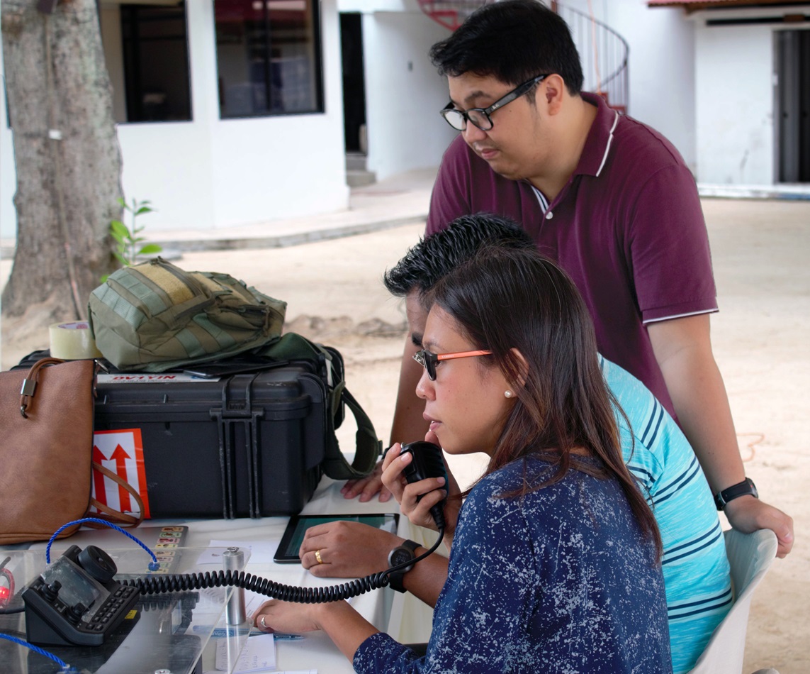 Peace and Conflict Journalism co-founder Len Manriquez (right) facilitates data gathering using a ham radio during a simulation in Cebu, Philippines. The Disasters and Emergency Preparedness Program was held June 27-29 to strengthen communications during times of crisis. Photo by Mildred Arce, UMNS.