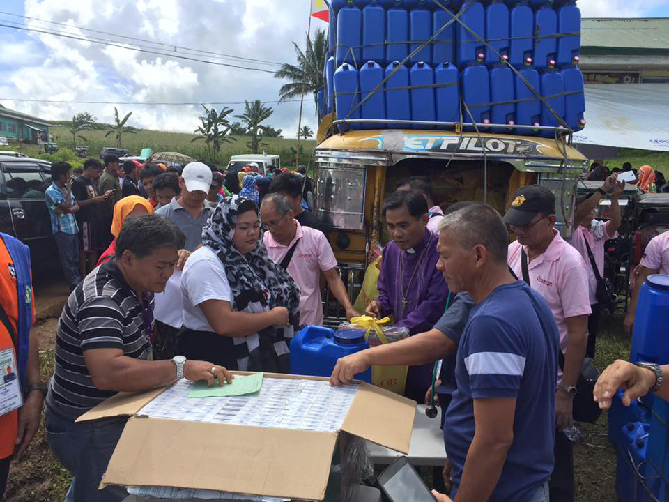 United Methodist volunteers, including Bishop Rodolfo A. Juan (in clerical collar), hand out relief supplies to families who fled fighting with Islamic State militants at an evacuation center in Bito-Buadi, Marawi City, Philippines. Photo by the Rev. Israel M Painit