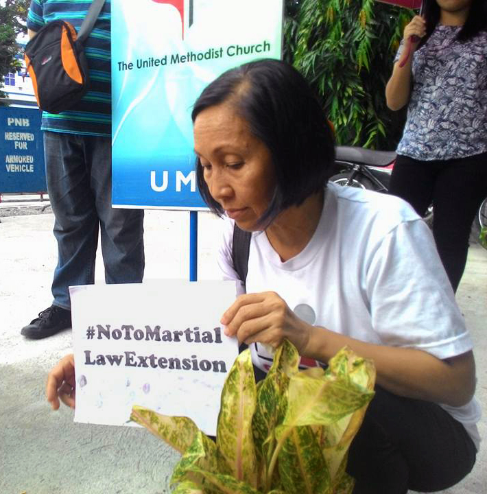 Phebe G. Crismo, executive secretary of the Board of Christian Education and Discipleship for the Philippines conference, holds a sign with the hashtag #NoToMartialLawExtension during a candle-lighting gathering in front of The United Methodist Church Headquarters in Manila. A 60-day martial rule proclamation for Mindanao expired on July 22, but the Filipino Congress voted to extend it through the end of the year. Photo by Liza Cortez.