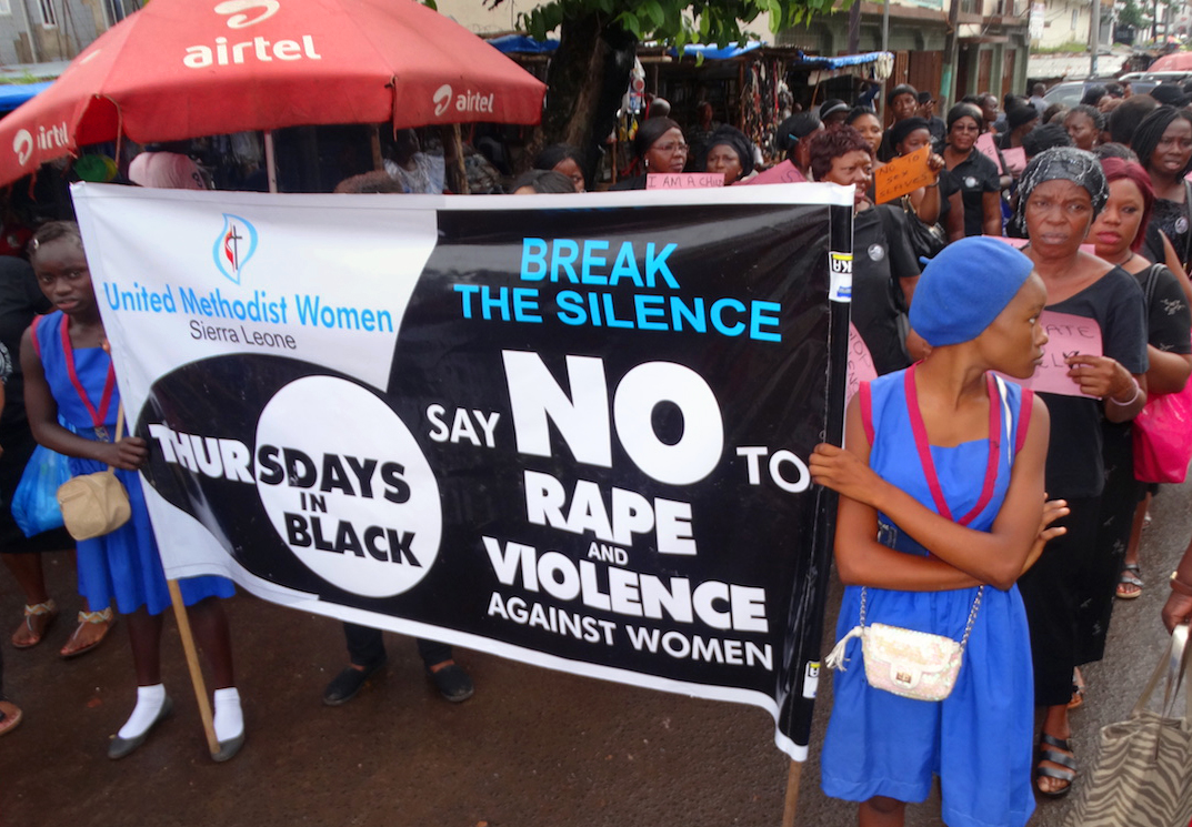 Two girls from the United Methodist Girls Secondary School carry an anti-violence banner in the procession of United Methodist Women of the Sierra Leone Annual Conference along the streets of Freetown on July 27. The women, all dressed in black, marched from UMC House — the conference’s head office — to King Memorial United Methodist Church, where United Methodist Women was holding its Western District Annual Convention. 