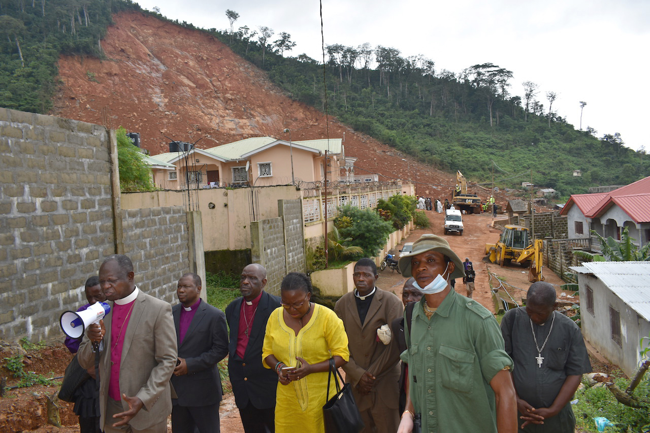 United Methodist Bishop John Yambasu (with megaphone) leads community members, relief workers and other clergy in prayer at the site of a massive mudslide that killed hundreds of people near Freetown, Sierra Leone. Photo by Phileas Jusu, UMNS