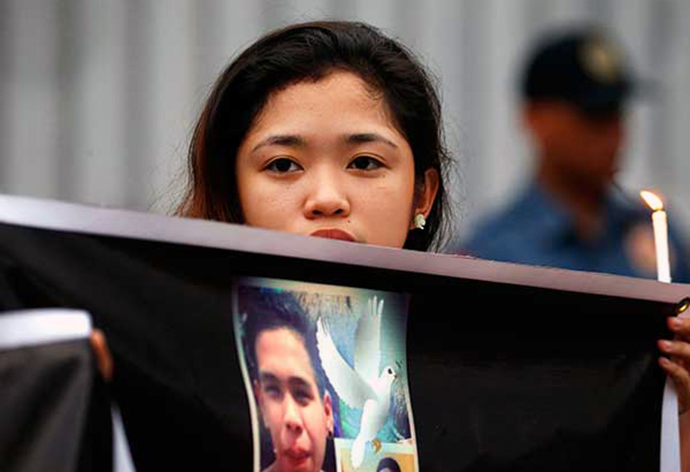 Aminah A. Lucena, a United Methodist youth, holds a photo of Kian delos Santos during a candle-lighting protest in front of the Philippine National Police headquarters in Quezon City on Aug. 23. Kian, a 17-year-old student, was a victim of extrajudicial killings under the Operation Galugad of the War on Drugs campaign of President Rodrigo Duterte. Photo by Miguel de Guzman, courtesy of The Philippine Star.