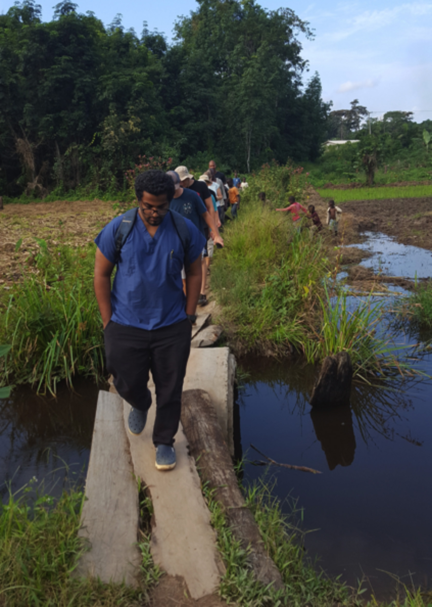 Dr. Shane Sam Mathew (front) leads a visit to a farm near Ganta United Methodist Hospital in Liberia. The 25-year-old dentist was killed in a fire at his residence. Photo courtesy of Ganta United Methodist Hospital.