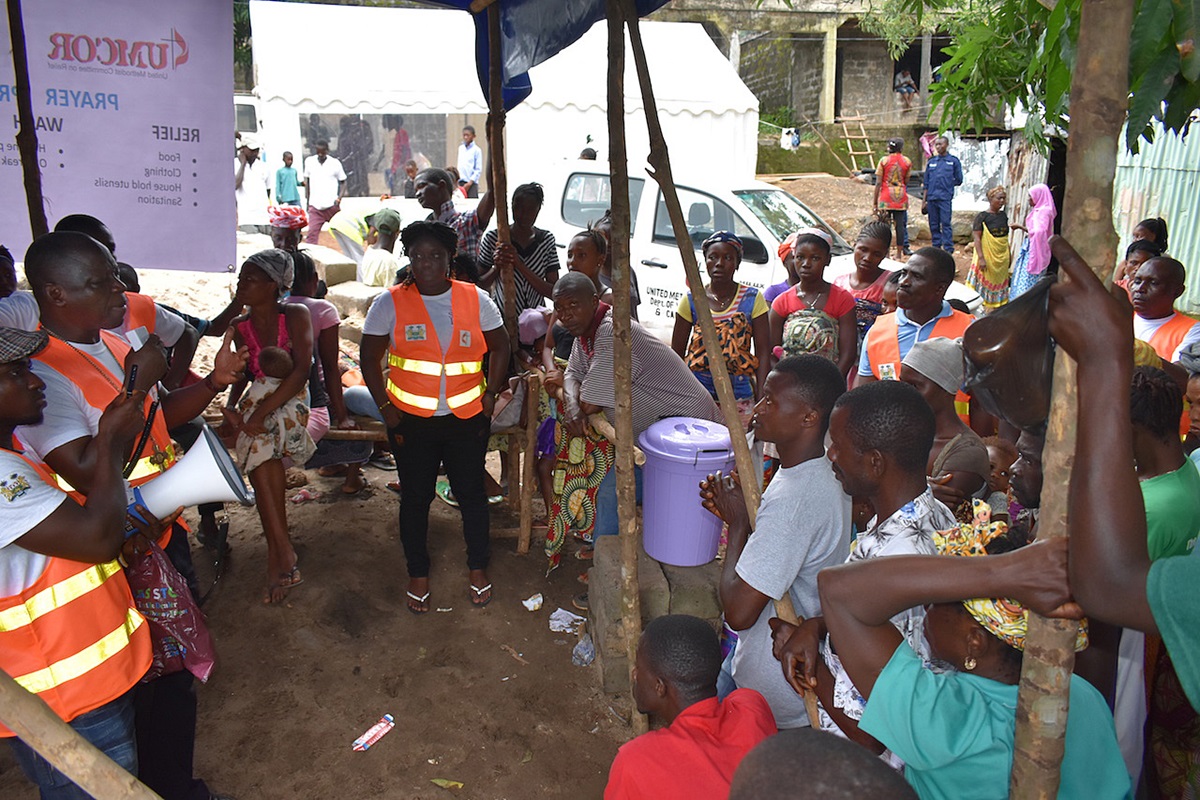 United Methodist Bishop John Yambasu (second from left) prays with people displaced by recent mudslides and flooding at a relief center in the Pentagon community, near Freetown, Sierra Leone. Photo by Phileas Jusu, UMNS.