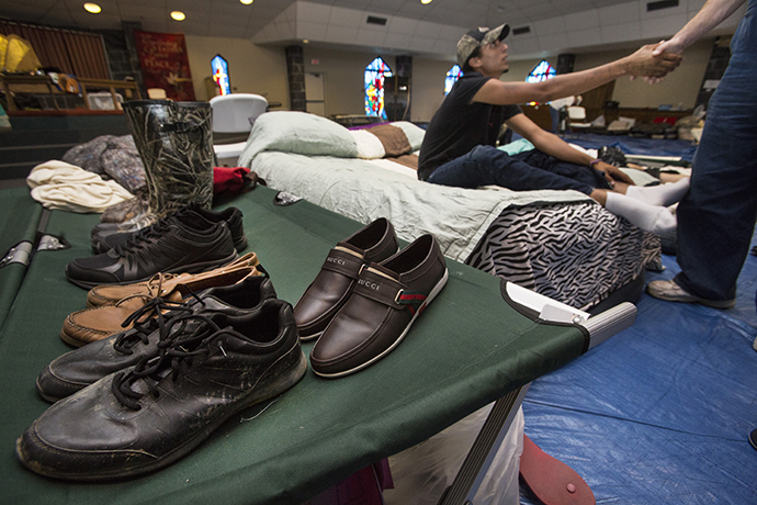 The gym at Woodcrest United Methodist Church in Lumberton, Texas, serves as a shelter to many including Stevon Ford (on cot) who is shaking the hand of Allen Smith. Smith, who was helping to run the shelter, has given Ford a job. Photo by Kathleen Barry, UMNS.