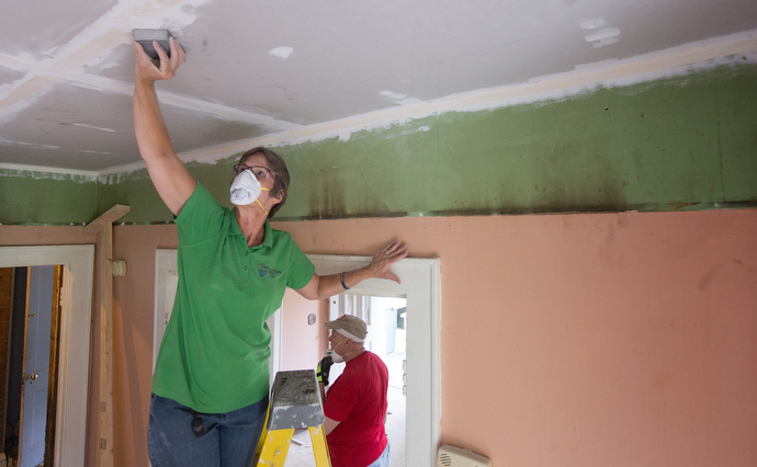 Bishop Sandra Steiner Ball of the West Virginia Conference of The United Methodist Church (on ladder) and members of her cabinet help repair a home near Rupert, W. Va., for a survivor of the severe floods that struck the area in June 2016. Photo by Mike DuBose, UMNS.