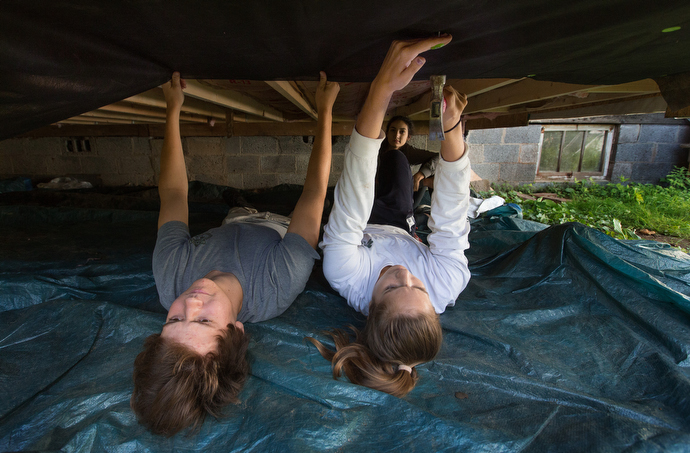 Volunteers Alex Hawthorne (left), Olivia DeMattia (right) and Anna Zahorchak (rear) of South Roanoke (Va.) United Methodist Church help repair a home in the Swinging Bridge community near Clay, W. Va., for a flood survivor. Photo by Mike DuBose, UMNS.