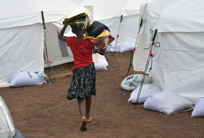 A disaster-displaced girl returns to her tent after collecting relief items distributed by the Council of Churches in Sierra Leone at a new relocation camp in Juba. Photo by Phileas Jusu, UMNS.