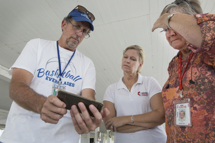 (From left) Jim Ragusa, principal of Everglades City School, shows photos of Hurricane Irma damage to the Rev. Laura Ice and Pam Garrison. Ragusa chose to ride out the storm with other residents.  Ice is recovery coordinator for the Florida Conference and Garrison is disaster response coordinator for the Florida Conference. Photo by Kathleen Barry, UMNS.