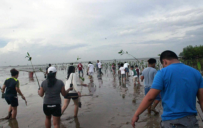 Lay people and youth from Greenhills United Methodist Church and Central United Methodist Church, led by the Rev. Jonathan  R. Ulanday, plant saplings during a DEA-wide tree planting across the Davao area of the Philippines on Oct. 14. A number of conferences, districts and local churches participated, led Bishop Rodolfo A. Juan. Photo by Apple Joy B. Lawag.