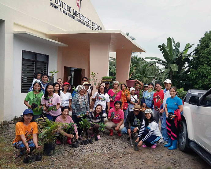 The Rev. Janeth Rufino (kneeling, fourth from left) pauses for a group photo before heading to a farm to plant fruit-bearing trees. More than 500 clergy and laity members from across the Davao area of the Philippines joined the endeavor. Photo courtesy of the Rev. Janeth Rufino.