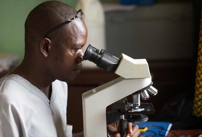 Andrew Brimah reads a microscope slide for tuberculosis at the Ganta Leprosy and TB Rehab Center. Photo by Mike DuBose, UMNS.
