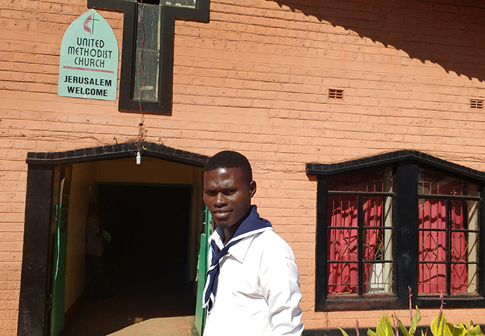 Misheck Mukumbi, a young adult at Jerusalem United Methodist Church, indicates the new water tank. He said having clean water by the church will help both the parish and community combat cholera. Photo by John Chikuta, UMNS.