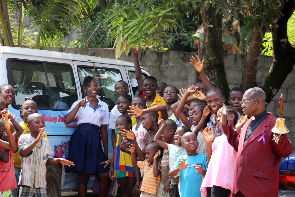 The Rev. Robert N. Sieh, director of The United Methodist Church’s Bishop Judith Craig Children’s Village, and children pose with their new bus.  Photo by E Julu Swen, UMNS.