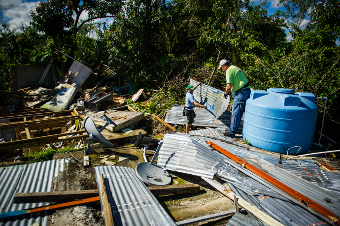 Nick Shelly (left) and the Rev. Mike Evans clear damaged metal roofing from a storm-devastated home in Hatillo before new construction begins. Photo by Matt Brodie.