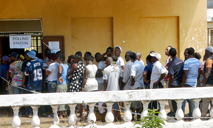 People stand in line to vote in multitier elections on March 7, 2018, outside The Great Hall of the Milton Margai College of Education and Technology at Goderich in rural Freetown, Sierra Leone. A runoff election for president will take place March 27 after no clear winner emerged on March 7. Photo by Phileas Jusu, UMNS.