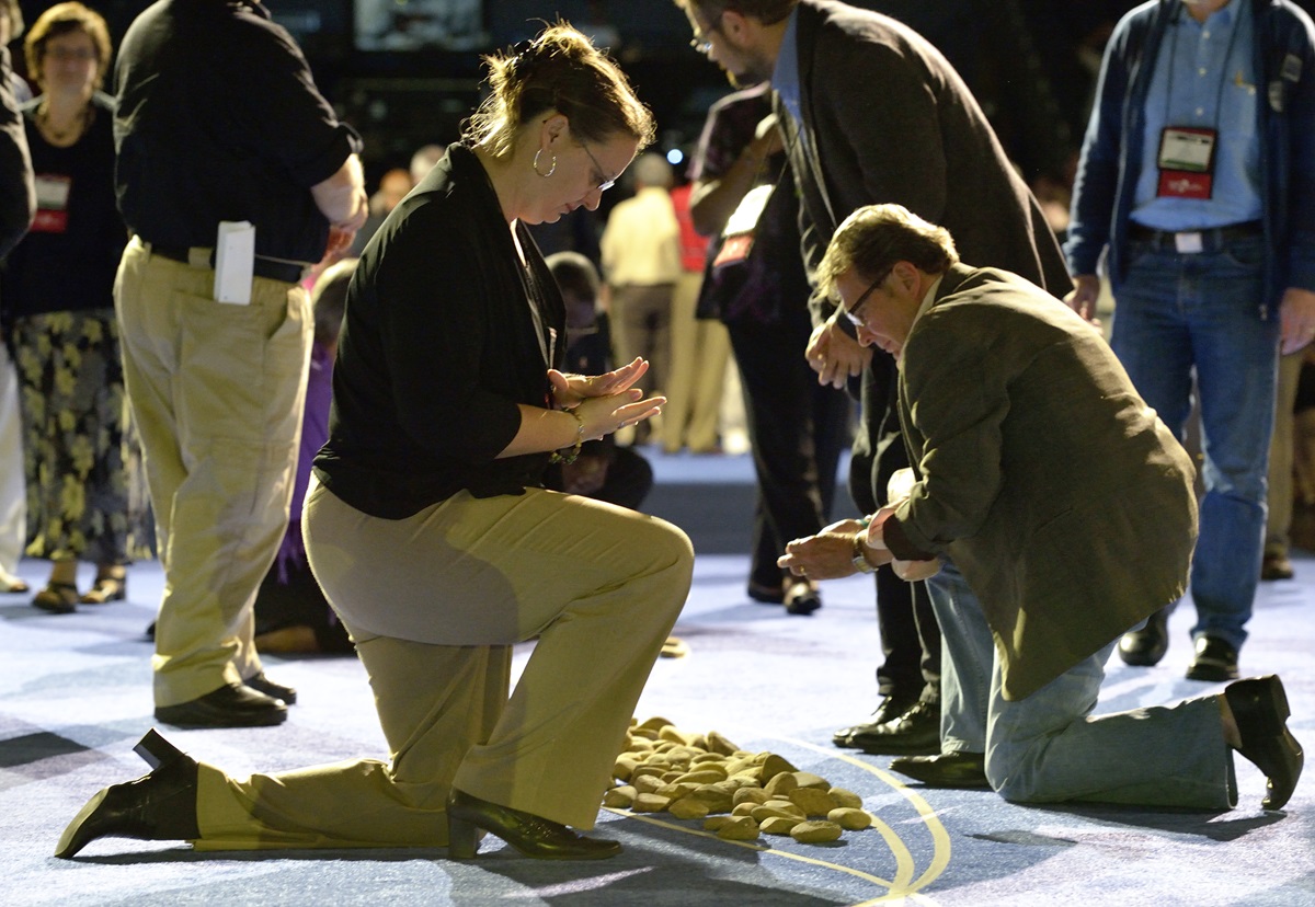 A delegate picks up and holds a stone in the center aisle during an April 27 "Act of Repentance toward Healing Relationships with Indigenous Peoples" at the 2012 United Methodist General Conference in Tampa, Florida. A UMNS photo by Paul Jeffrey.