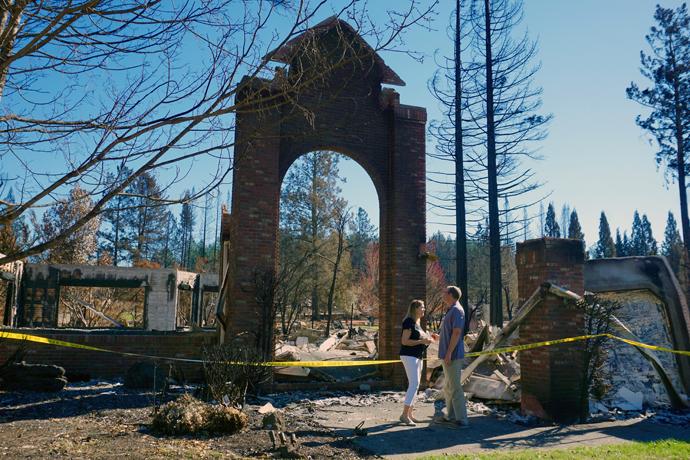 The Rev. Blake Busick and his wife, Peggy, stand in front of their Santa Rosa home after it was destroyed by the California wildfires that started on Oct. 9. Photo by Sue Larson, courtesy of the Rev. Blake Busick.