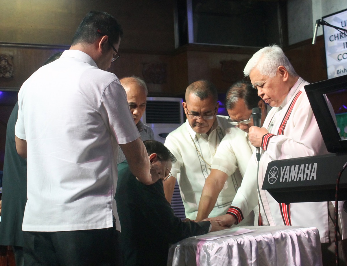 Bishop Daniel Arichea Jr. offers a prayer for Reynato S. Puno, kneeling, as other Filipino bishops and district superintendents lay hands on the former chief justice at a prayer gathering March 22 at Puno United Methodist Church in Diliman, Quezon City, Philippines. Puno, a United Methodist, was chosen by Philippines President Rodrigo Duterte to lead a Consultative Committee for Charter Change. Photo by Gladys Mangiduyos, UMNS.