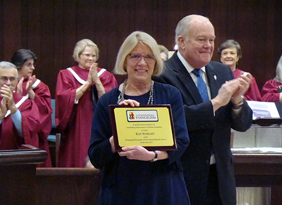 Kay Schecht, standing with Bishop Mike McKee, accepts the Foundation for Evangelism’s Distinguished Evangelist Award during the April 8 worship service at Plymouth Park United Methodist Church, in Irving, Texas. Photo by Bill Fentum.