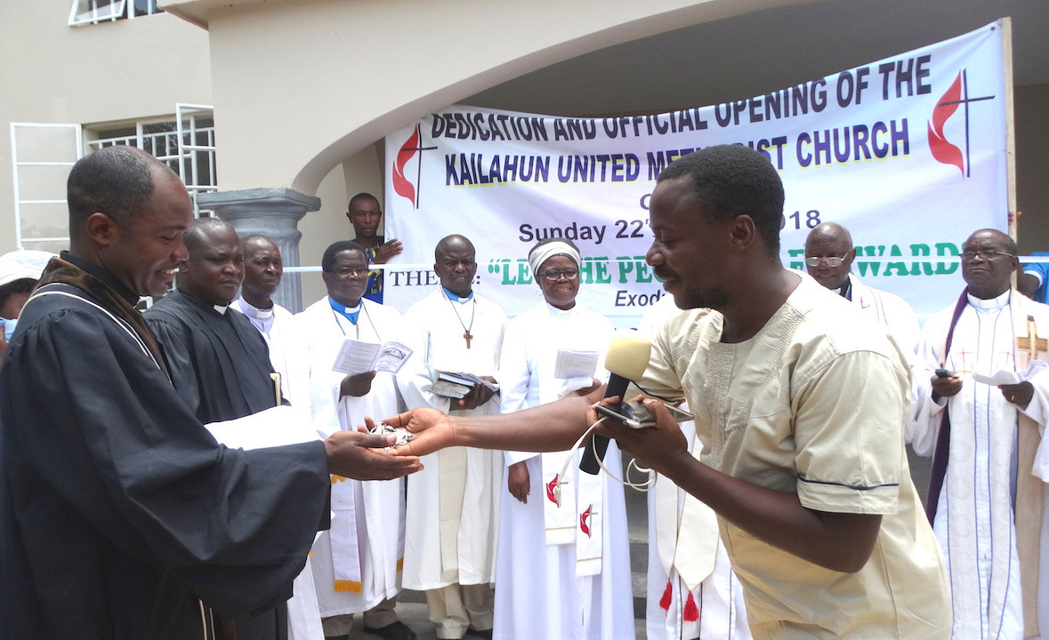 A building engineer (right) hands over the keys of Grace United Methodist Church to the Rev. Samuel Kailie, pastor in charge of the new church in Kailahun, Sierra Leone, during a dedication ceremony in April. Photo by Phileas Jusu, UMNS.