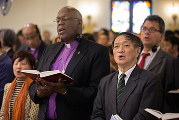 The Rev. Bao Jiayuan (right foreground) is flanked by United Methodist Bishop Warner Brown (left foreground) and Thomas Kemper of the denomination's Board of Global Ministries during worship at Chongwenmen Church in Beijing, China. Bao's work with the China Christian Council has made him the council's good-natured ambassador to Christians and interfaith representatives worldwide.