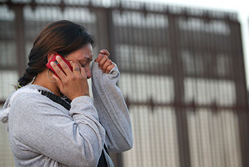 Nancy, who was deported from the U.S. after a traffic violation, cries as she speaks with her mother in Los Angeles from the Mexican side of the massive border fence in Tijuana.