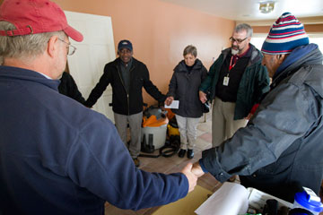 The Rev. Tom Hazelwood (second from right) of the United Methodist Committee on Relief leads a prayer at a home damaged by floodwaters from Hurricane Sandy in Massapequa, N.Y. A UMNS photo by Mike DuBose.