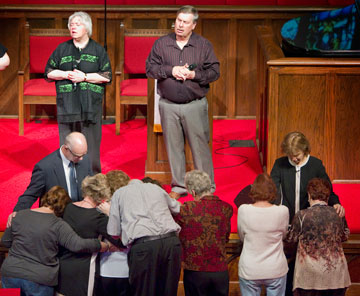 Bishop Debra Wallace-Padgett (right) and the Rev. Bob Alford pray with parishioners during the closing hymn.