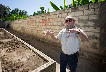 Warren McGuffin shows the raised-bed garden where okra has been planted at the Thomas Food Project.