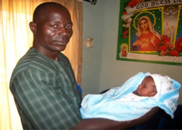 Coordinator Simon Benjamin holds a 2-day-old baby boy whose mother died.