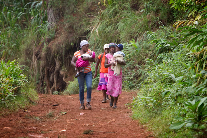 Mothers carry their children down a muddy trail after a visit to the Methodist Churchs health clinic in Furcy.