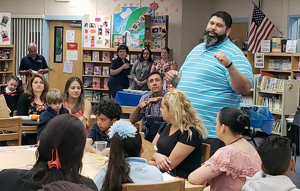 The Rev. Jose Nieves (standing, foreground) meets at Boggy Creek Elementary with families who were displaced from Puerto Rico by Hurricane Maria and have relocated to Kissimmee, Fla. Photo by Linda Logston.
