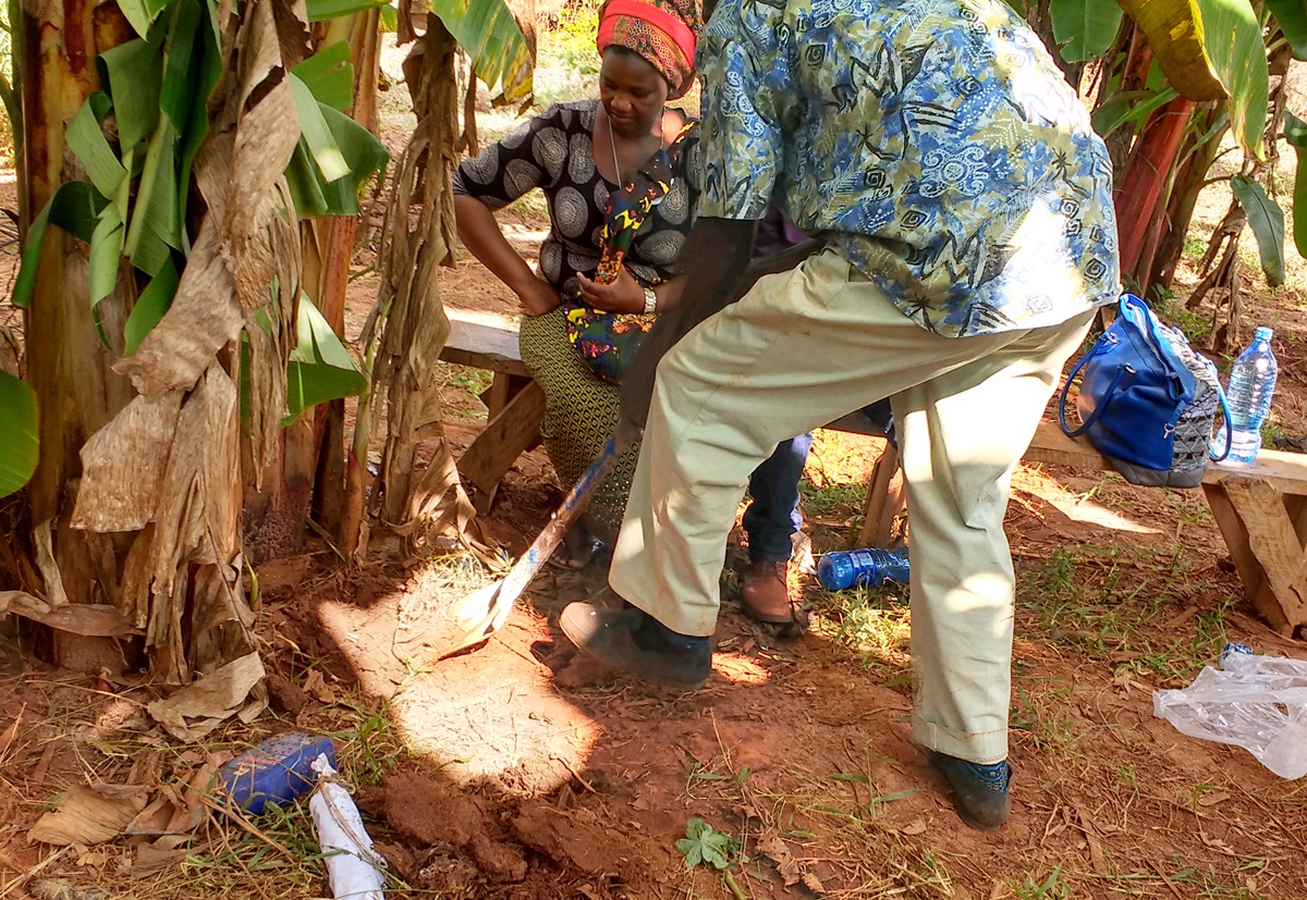 A woman watches as teacher Mwita Baita Baitele digs a hole during a training session on organic farming in Dar es Salaam, Tanzania, in April. Members of United Methodist Women gathered to share what they eat every day and where and how they grow their food. Photo by the Rev. Betty Kazadi Musau, UMNS