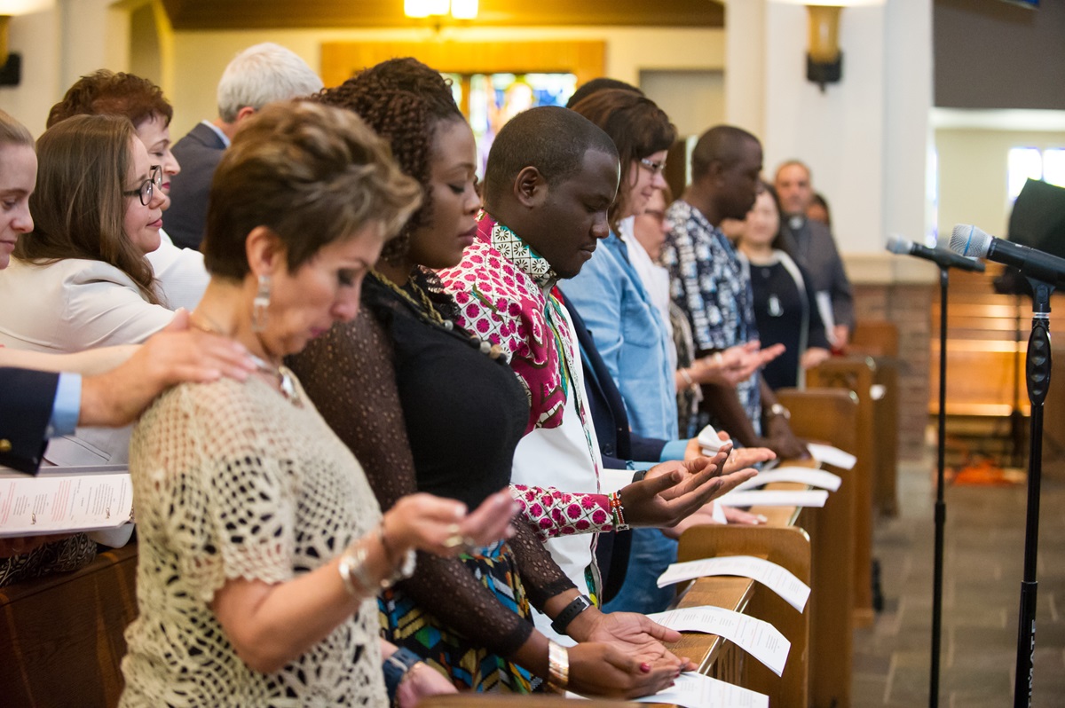 Los/as misioneros/as extienden sus manos para recibir la bendición, durante el servicio de consagración.