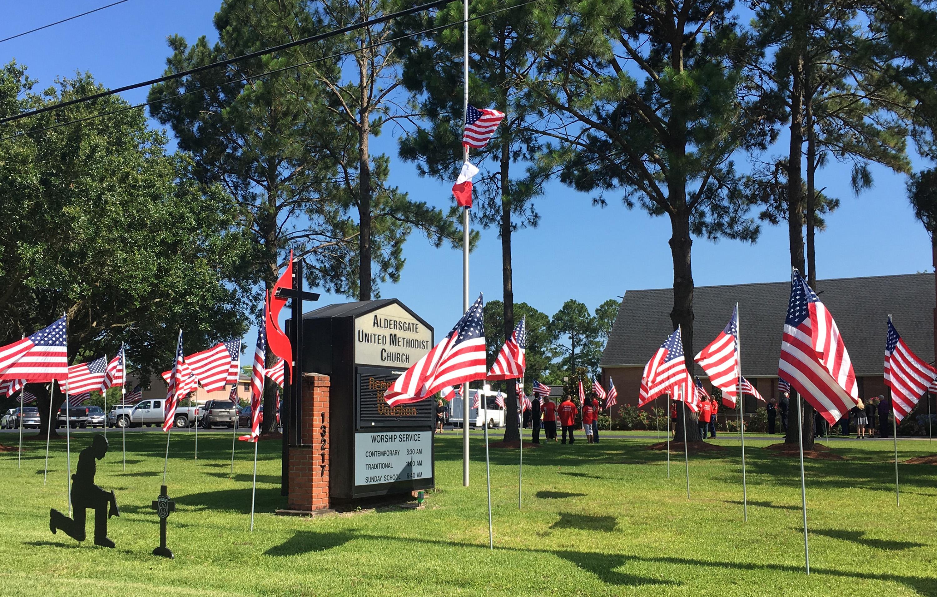 The flag on the main flagpole outside Aldersgate United Methodist Church in Santa Fe, Texas, flies at half-staff in memory of shooting victims at Santa Fe High School, including church member Jared Black, 17. The other flags on the lawn are part of the church’s Memorial Day display and the kneeling figure honors fallen police officers. Photo by Sherri Gragg, Cross Connection