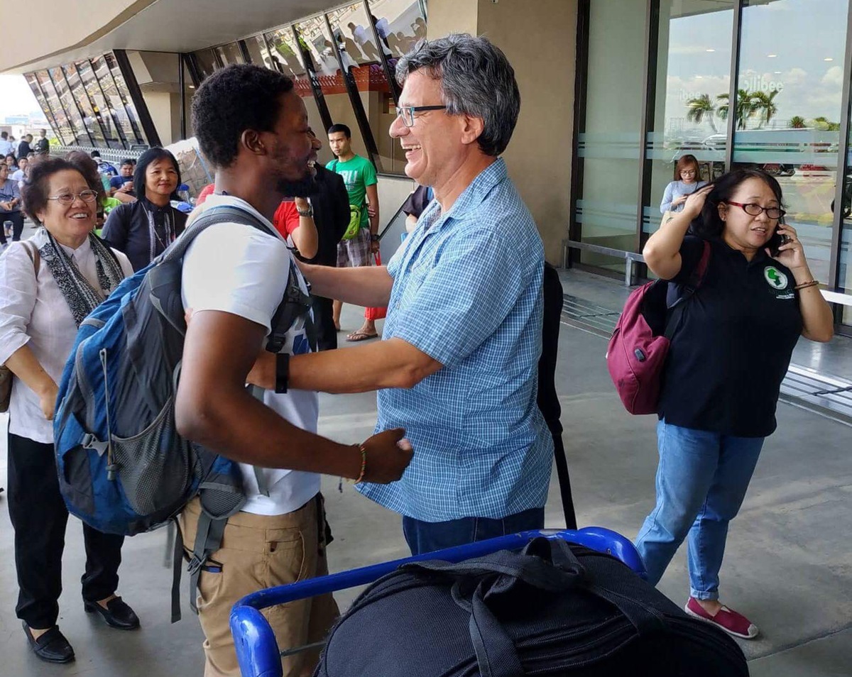 United Methodist missionary Tawanda Chandiwana (left foreground) is embraced by Thomas Kemper, head of the denomination’s Board of Global Ministries, at the Ninoy Aquino International Airport in Manila, Philippines, after Chandiwana was released from a detention center and allowed to leave the country. Photo courtesy of Thomas Kemper, GBGM. United Methodist missionary Tawanda Chandiwana (left foreground) is embraced by Thomas Kemper, head of the denomination’s Board of Global Ministries, at the Ninoy Aquino International Airport in Manila, Philippines, after Chandiwana was released from a detention center and allowed to leave the country. Photo courtesy of Thomas Kemper, GBGM.