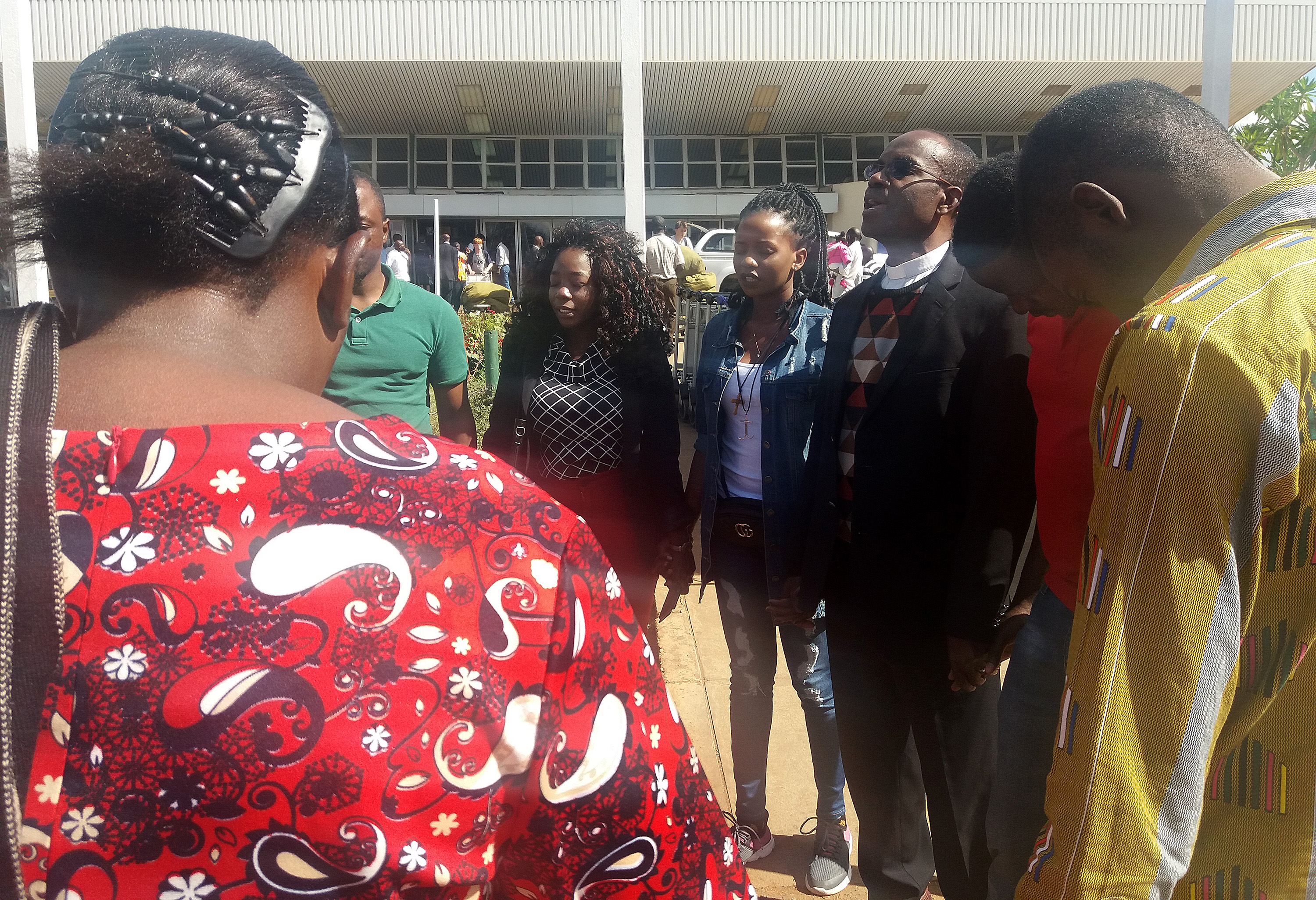 Church leaders and supporters pray with United Methodist missionary Miracle Osman (center, wearing white shirt) upon her arrival in Lilongwe, Malawi, after she was allowed to leave the Philippines. Photo courtesy of United Methodist Board of Global Ministries. 