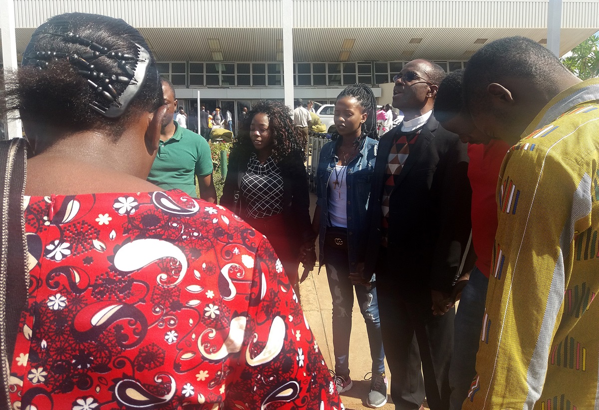 Church leaders and supporters pray with United Methodist missionary Miracle Osman (center, wearing white shirt) upon her arrival in Lilongwe, Malawi, after she was allowed to leave the Philippines. Photo courtesy of United Methodist Board of Global Ministries.  Church leaders and supporters pray with United Methodist missionary Miracle Osman (center, wearing white shirt) upon her arrival in Lilongwe, Malawi, after she was allowed to leave the Philippines. Photo courtesy of United Methodist Board of Global Ministries.