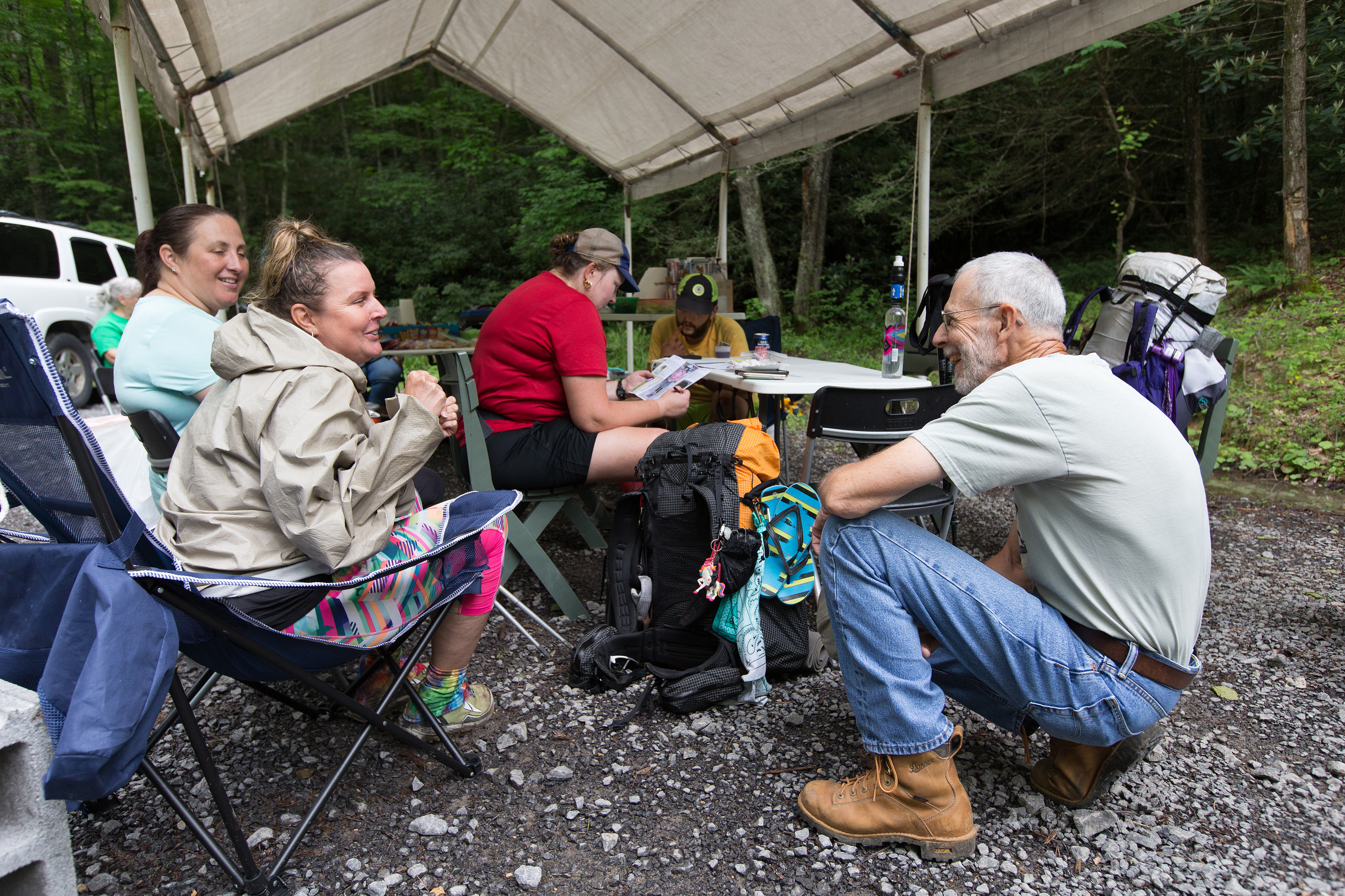 The Rev. Alan Ashworth (right) visits with Appalachian Trail thru-hikers at a free hiker feed sponsored by New Hope Union United Methodist Church near Bastian, Va. Volunteers set up a temporary shelter where the trail crosses a gravel parking area and offered hot sandwiches, salads and cold drinks to weary hikers. Photo by Mike DuBose, UMNS.