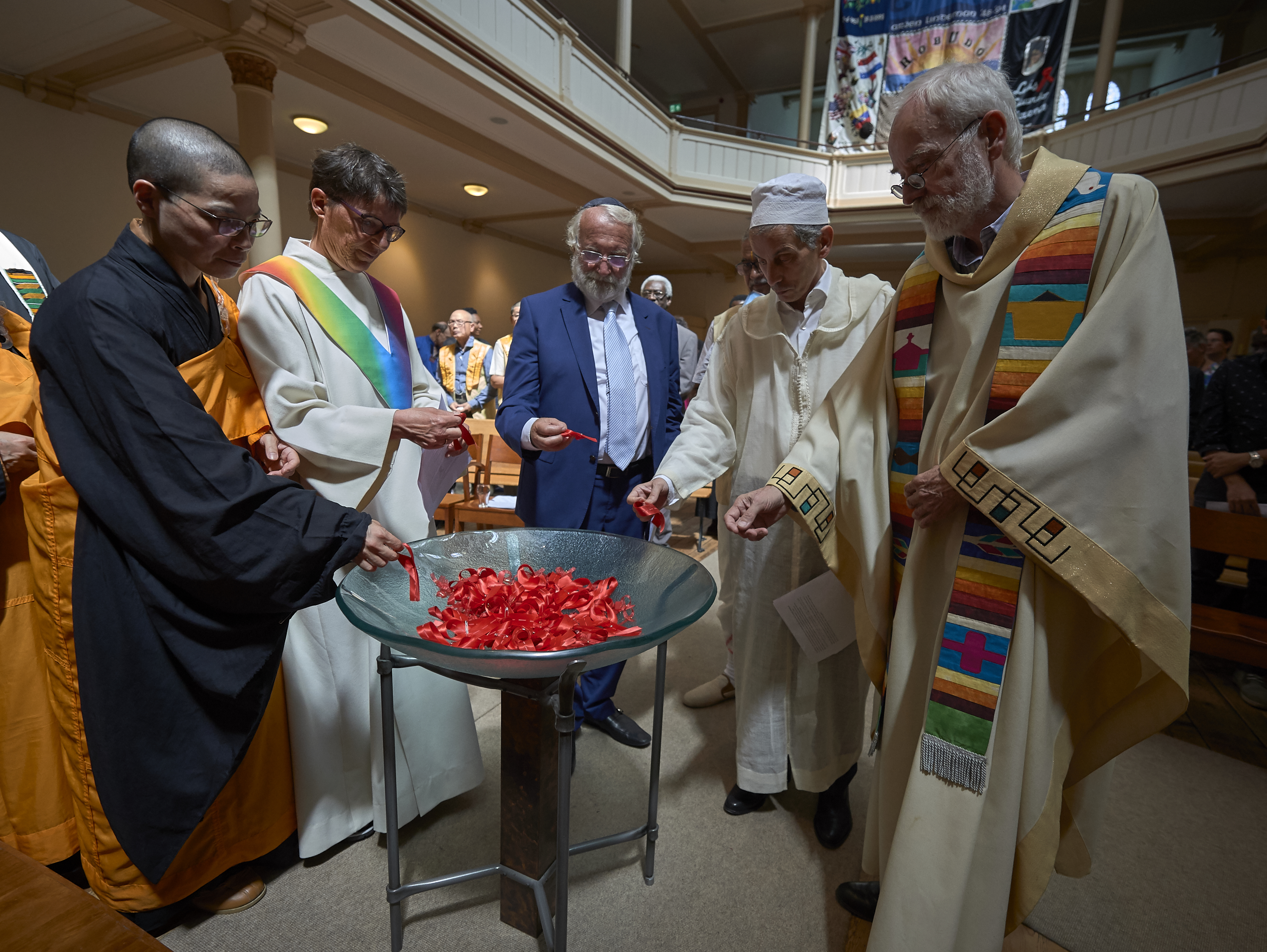Religious leaders from several traditions collected red ribbons, a sign of hope amid the HIV crisis, to place on a symbolic bridge during a July 23 interfaith prayer and memorial service in the Keizersgrachtkerk in Amsterdam. Sponsored by the World Council of Churches’ Ecumenical Advocacy Alliance, the service was held on the first day of the 2018 International AIDS Conference. Photo by Paul Jeffrey.