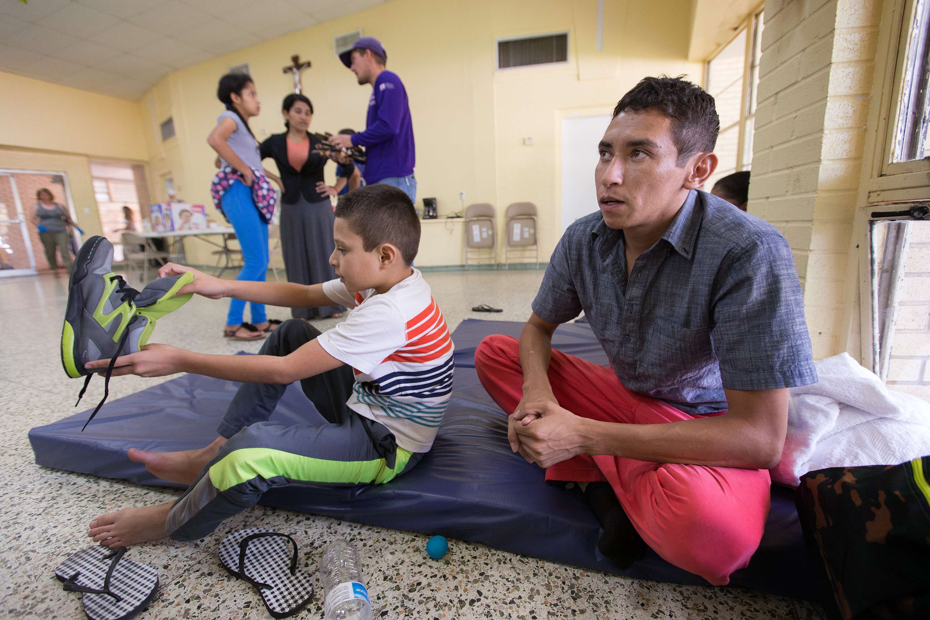 Oliver (right) and his 8-year-old son Anthony rest at an overflow shelter for recent immigrants at the Basilica of Our Lady of San Juan del Valle in McAllen, Texas. They fled their native Honduras in fear of gang violence and asked that their real names not be used.