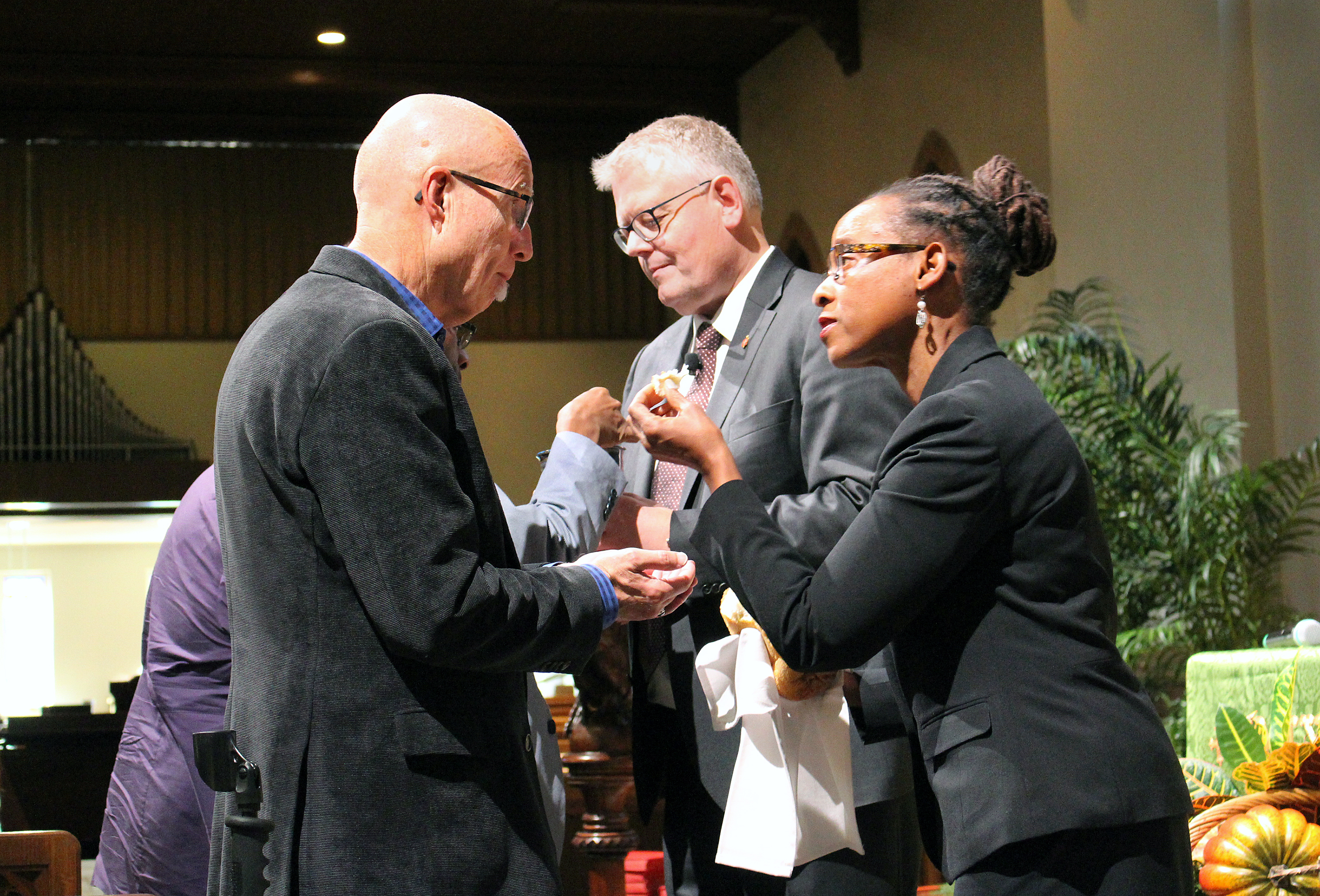 The Connectional Table opens its Oct. 31-Nov. 2 meeting in Atlanta with Holy Communion. From left, the Rev. Mike Slaughter receives the sacrament from Bishop Christian Alsted, Connectional Table chair, and the Rev. Kennetha Bigham-Tsai, chief connectional ministries office. Photo by Emily Clemons, Connectional Table.