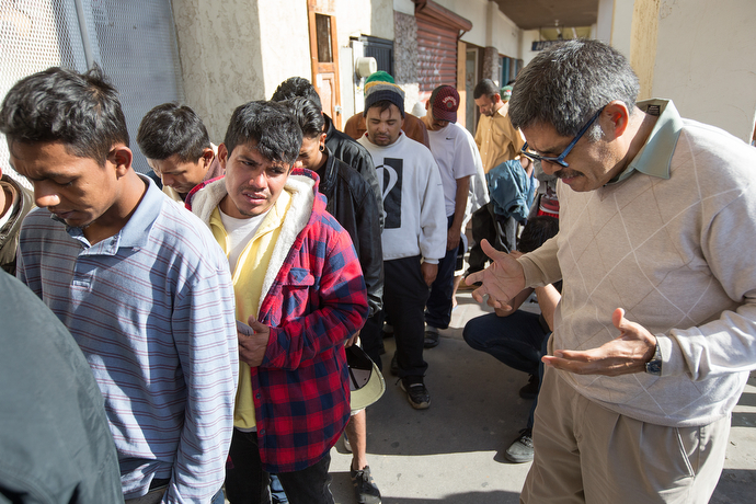 Bishop Felipe Ruiz Aguilar of the Methodist Church of Mexico prays with migrants outside El Divino Redentor Methodist Church in Mexicali as they wait to receive meals and hygiene kits.