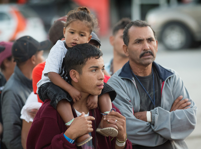 Central American migrants living at the Barretal shelter in Tijuana, Mexico, line up for a distribution of donated clothing.