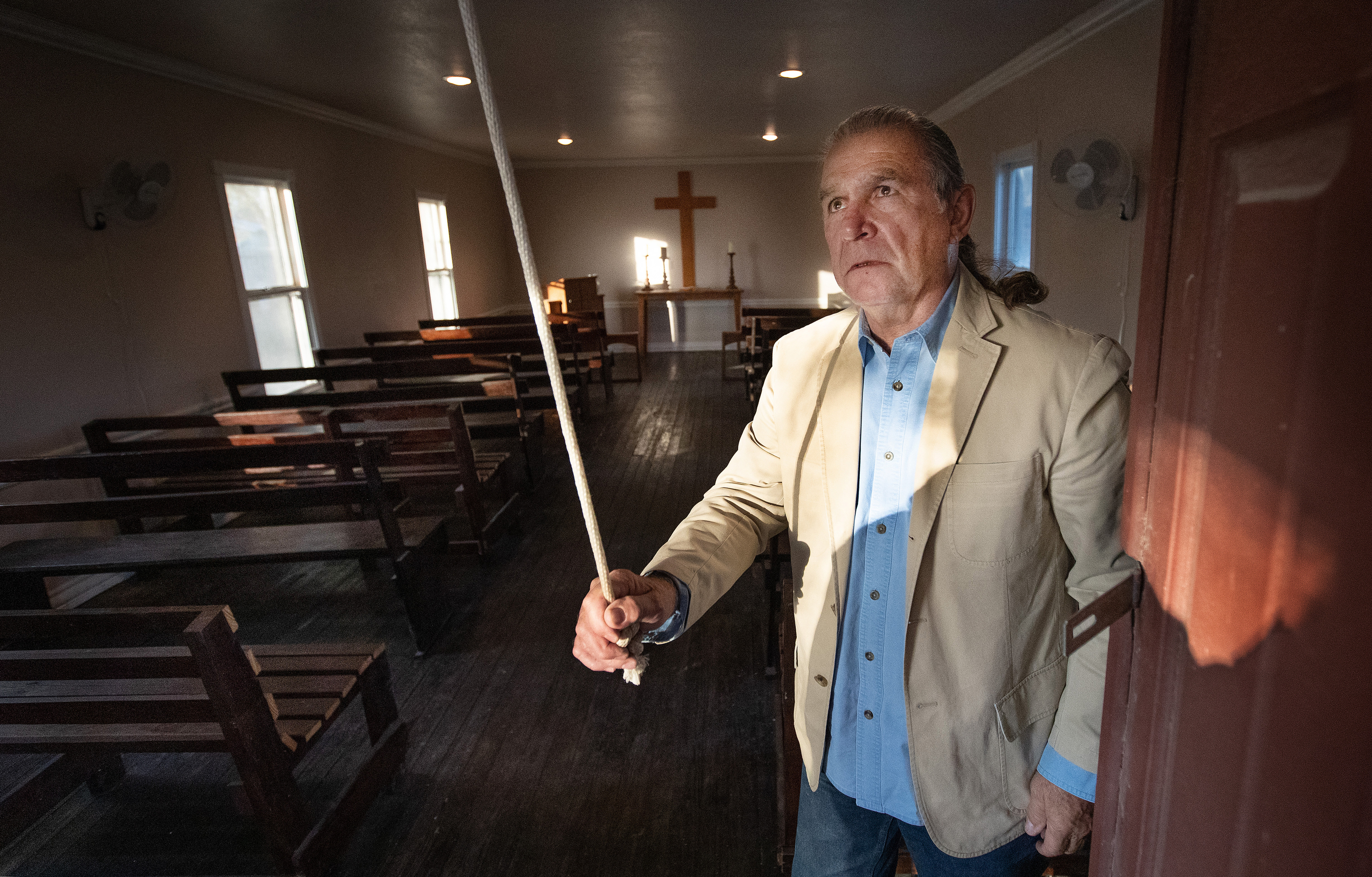 Ramiro Ramírez toca a campainha da Igreja Metodista Unida de Jackson Chapel em San Juan, Texas. A família de Ramírez doou terras para a igreja, que foi estabelecida em 1874. O muro de fronteira proposto pelo presidente Trump está programado para percorrer a propriedade da igreja, incluindo seu cemitério histórico. Foto de Mike DuBose, SMUN.