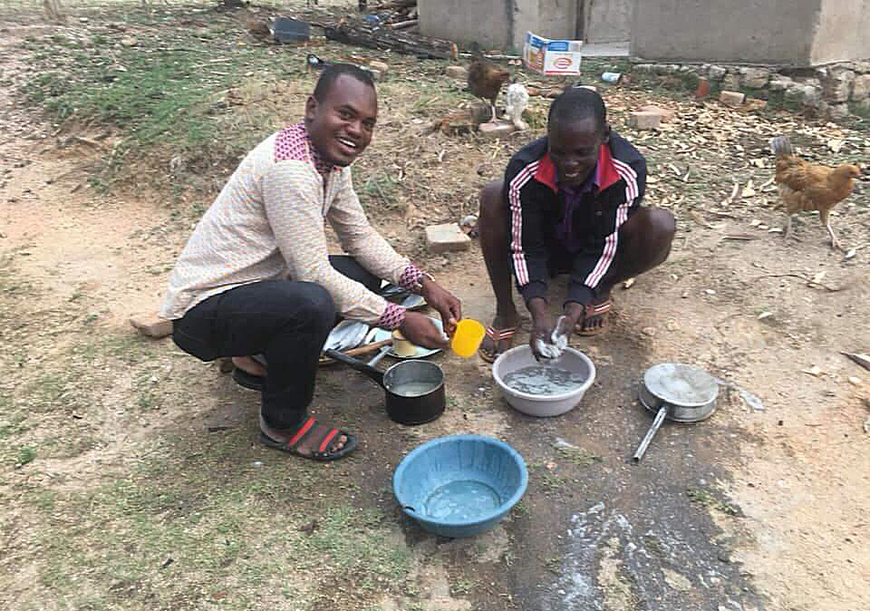 Cesar Lodiha Akoka washes dishes alongside a neighbor at Manica bridge shopping center in the Mutasa Nyanga community in Mutare, Zimbabwe. Akoka is one of several Africa University students working with local United Methodist congregations while studying abroad. Photo by Chenayi Kumuterera, UMNS.