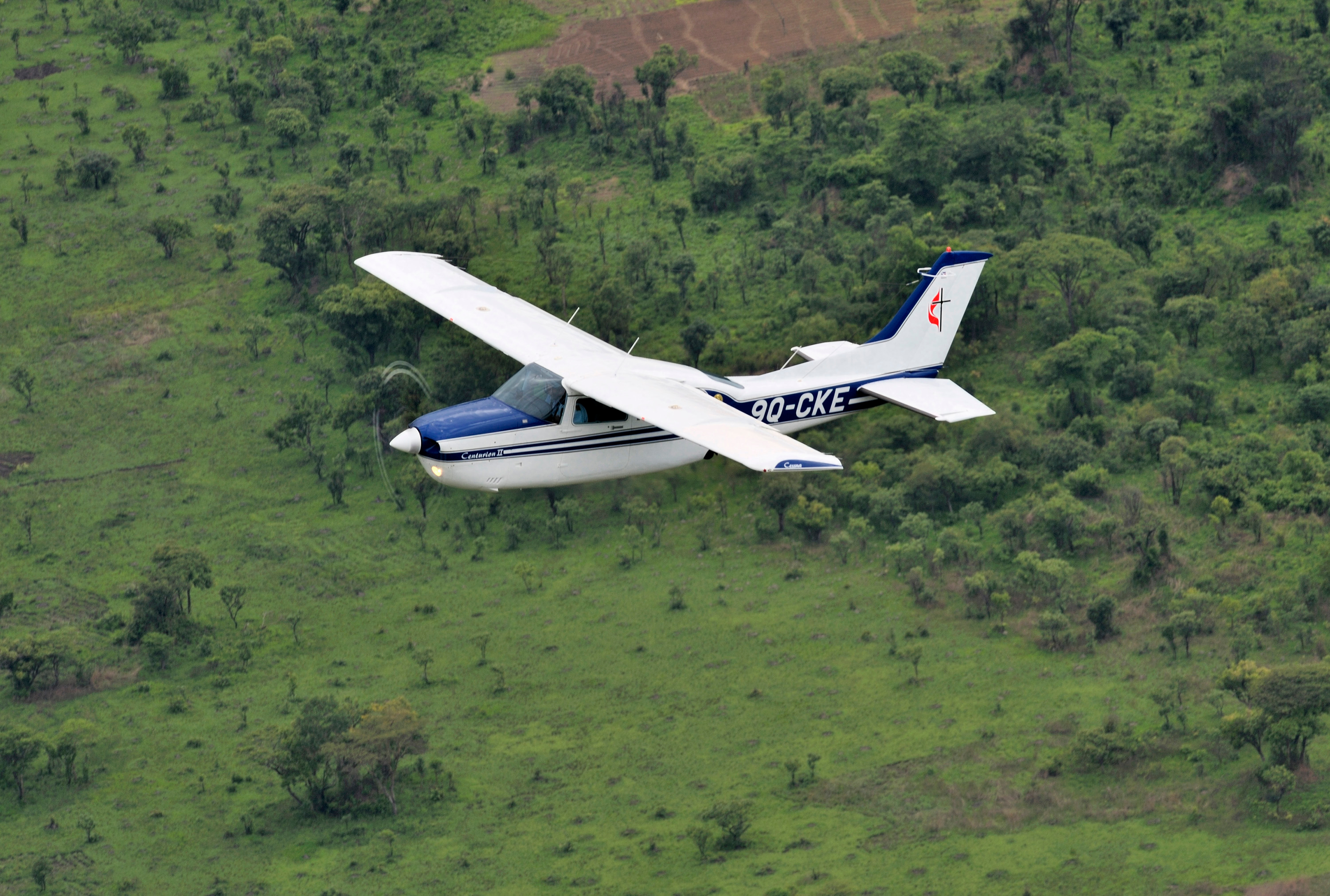A Cessna T210 piloted by Rukang Chikomb flies through the skies over Congo in 2008. Part of the Wings of the Morning aviation ministry of The United Methodist Church, the program provides life-saving access to isolated rural communities. The photo was taken from another plane, a Cessna P210 piloted by Gaston Ntambo, that is part of the same program. File photo by Paul Jeffrey. 